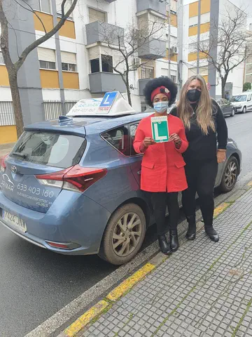 Dos alumnos de Autoescuela Larimar con la placa L junto al coche de prácticas (foto 22)