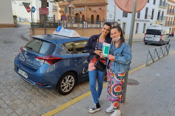 Dos alumnos de Autoescuela Larimar con la placa L junto al coche de prácticas (foto 11)
