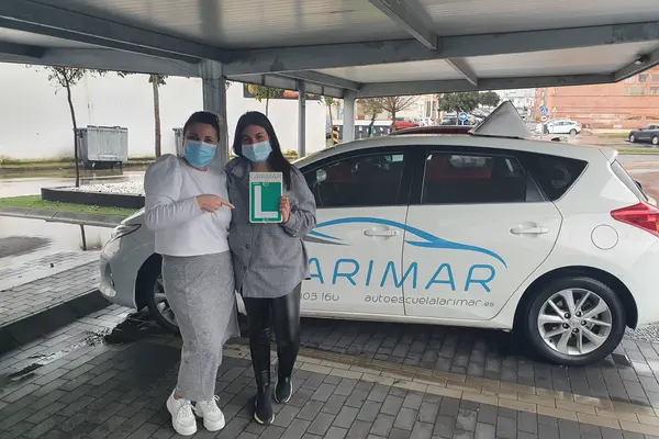 Dos alumnos de Autoescuela Larimar con la placa L junto al coche de prácticas (foto 18)