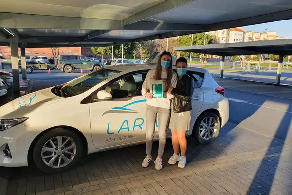 Dos alumnos de Autoescuela Larimar con la placa L junto al coche de prácticas (foto 16)