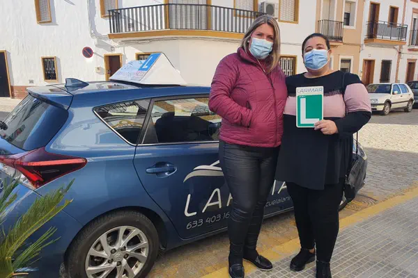 Dos alumnos de Autoescuela Larimar con la placa L junto al coche de prácticas (foto 12)