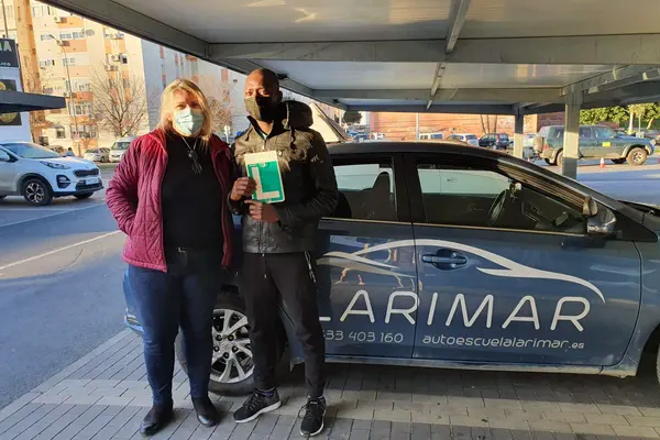 Dos alumnos de Autoescuela Larimar con la placa L junto al coche de prácticas (foto 15)