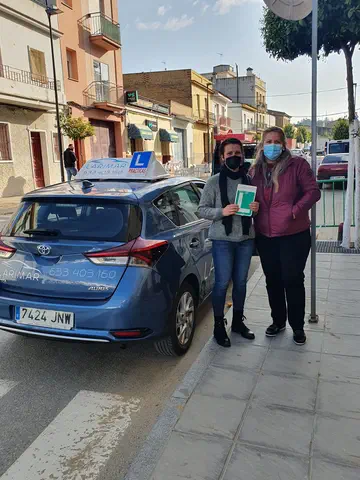 Dos alumnos de Autoescuela Larimar con la placa L junto al coche de prácticas (foto 20)